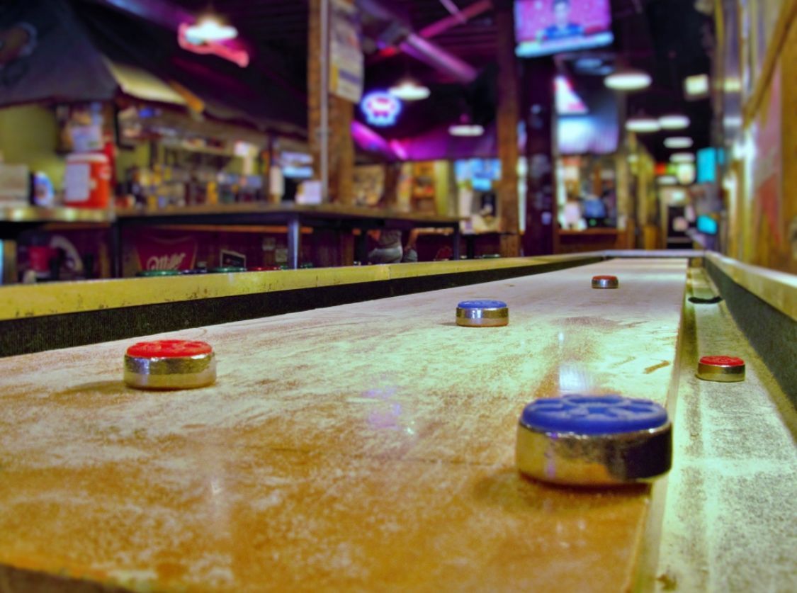 A shuffleboard game is being played in a bar.