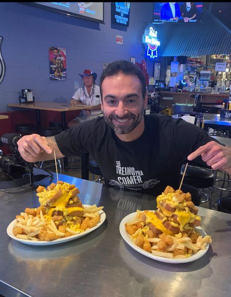 A man is sitting at a table with two plates of food on it.