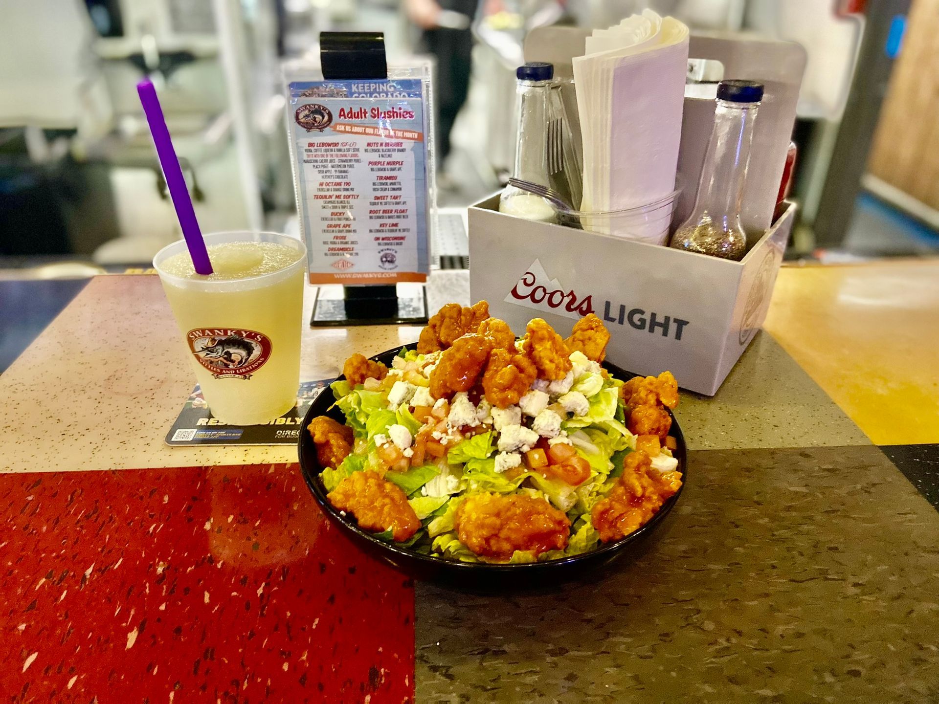 A salad and a drink are on a table at swankys sports bar in denver colorado