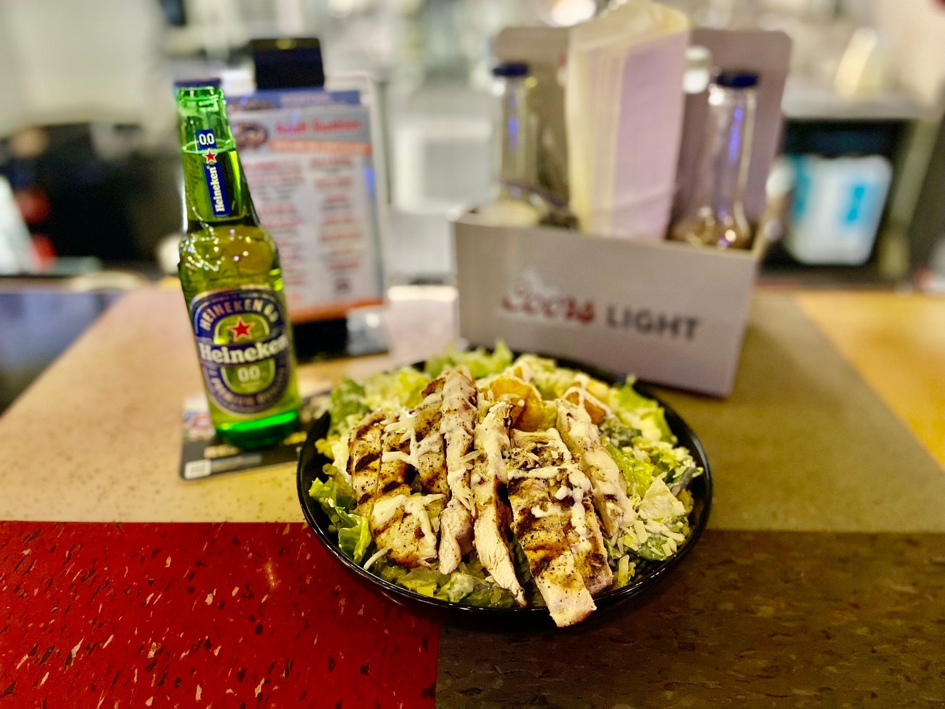 A plate of food and a bottle of beer are on a table.