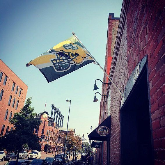 A green bay packers flag is hanging from the side of swankys, denver's #1 midwest sports bar near coors field