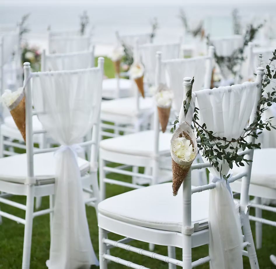 A row of white chairs decorated for a wedding ceremony