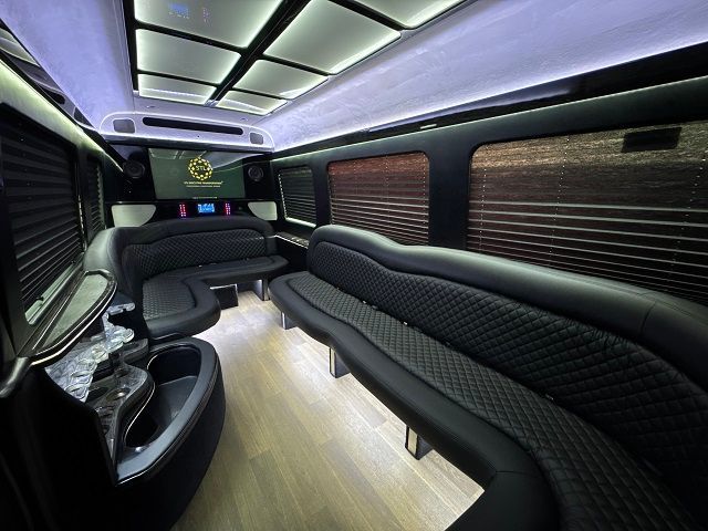 The inside of a limousine with a couch and a bar.