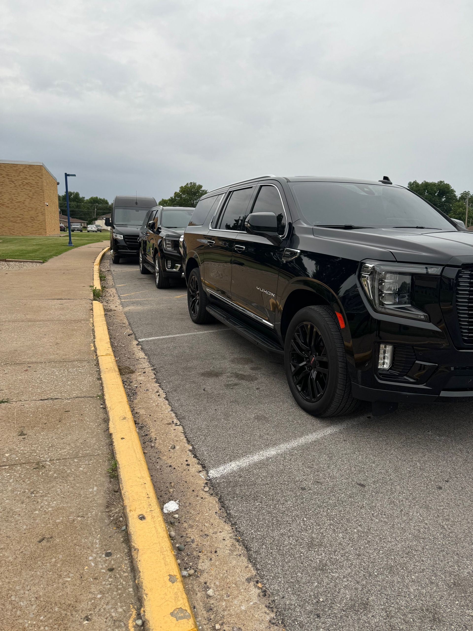 A row of black cars are parked next to each other in a parking lot.