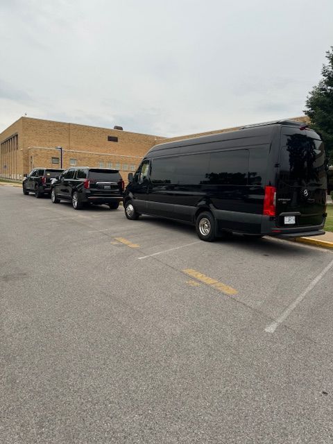 A row of black vans are parked in a parking lot.