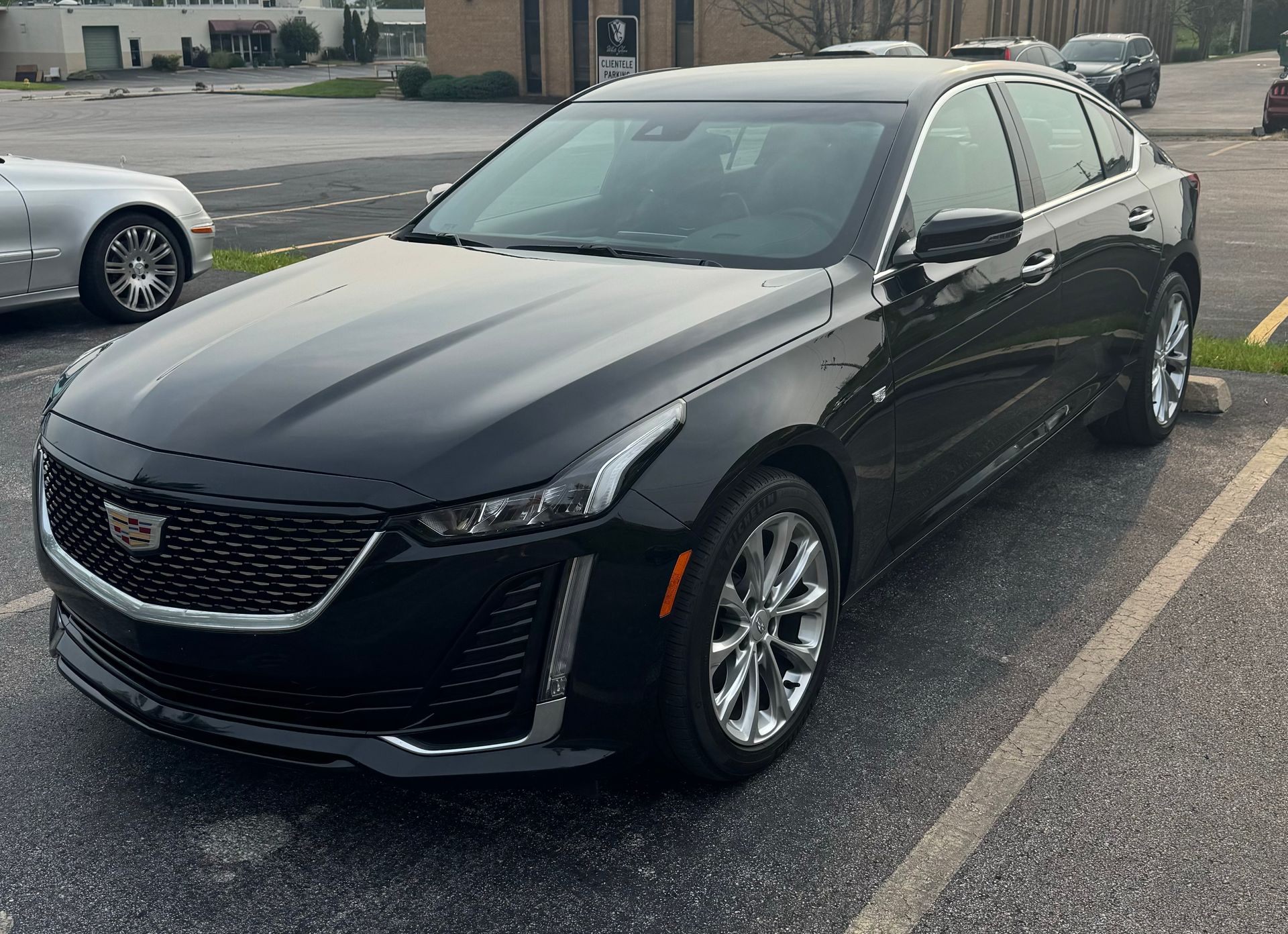 A black cadillac is parked in a parking lot.