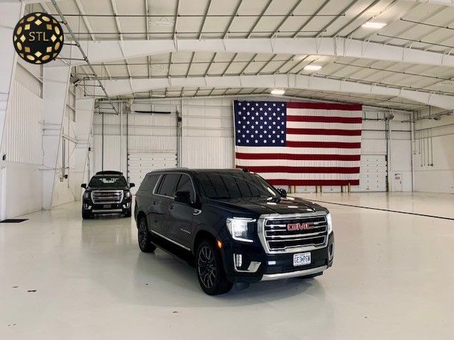 A gmc suv is parked in a garage with an american flag in the background.