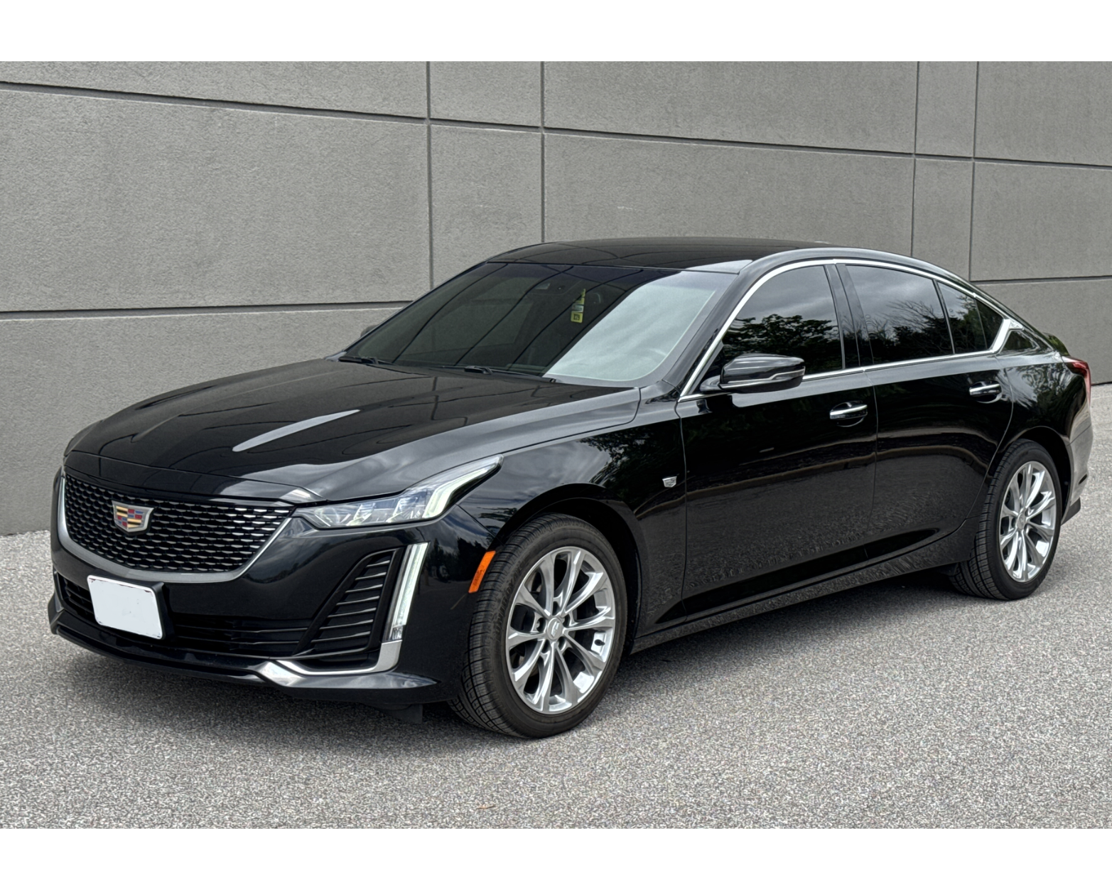 A black cadillac is parked in a parking lot.