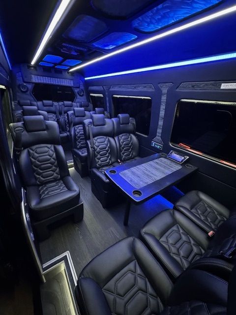 The inside of a van with black leather seats and a table.