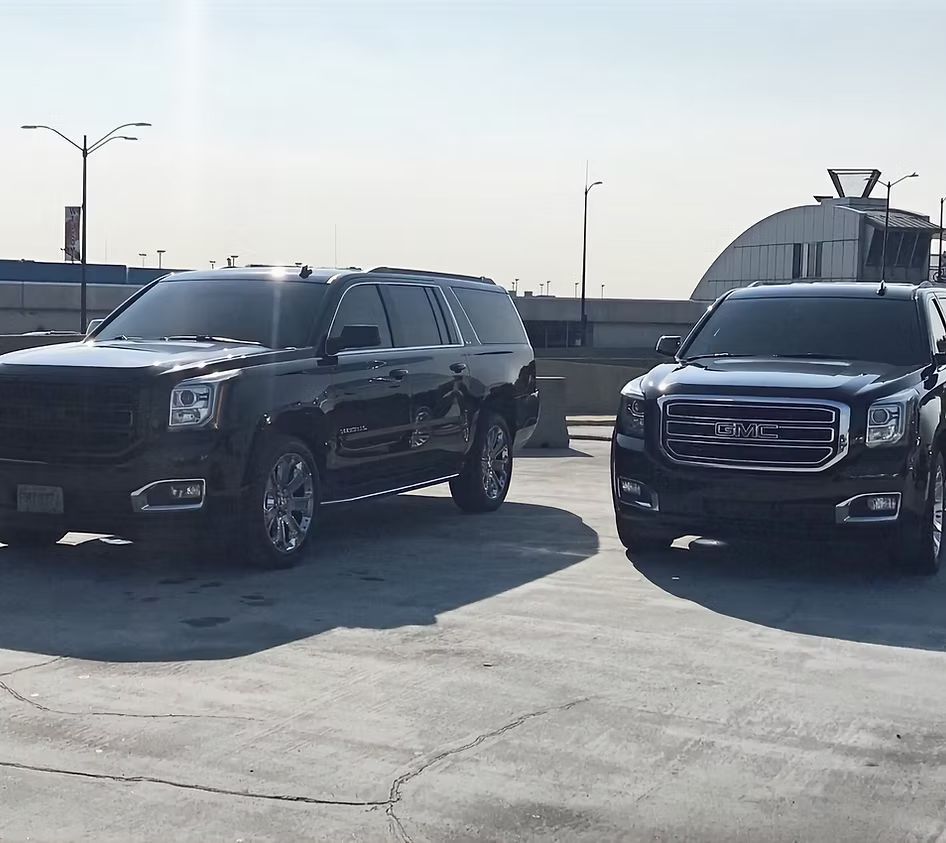 Two black suvs are parked next to each other in a parking lot