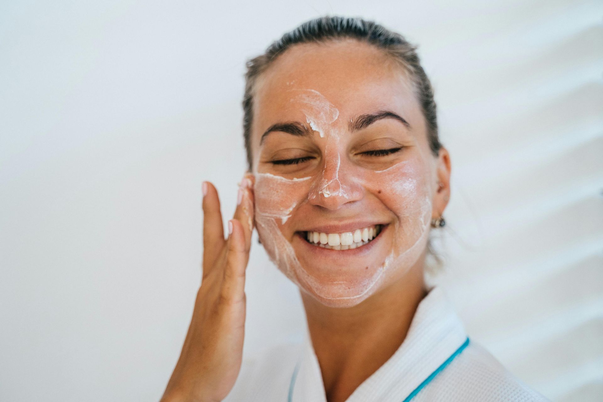 A woman applying skin cream to her face for maintaining proper skin health. 