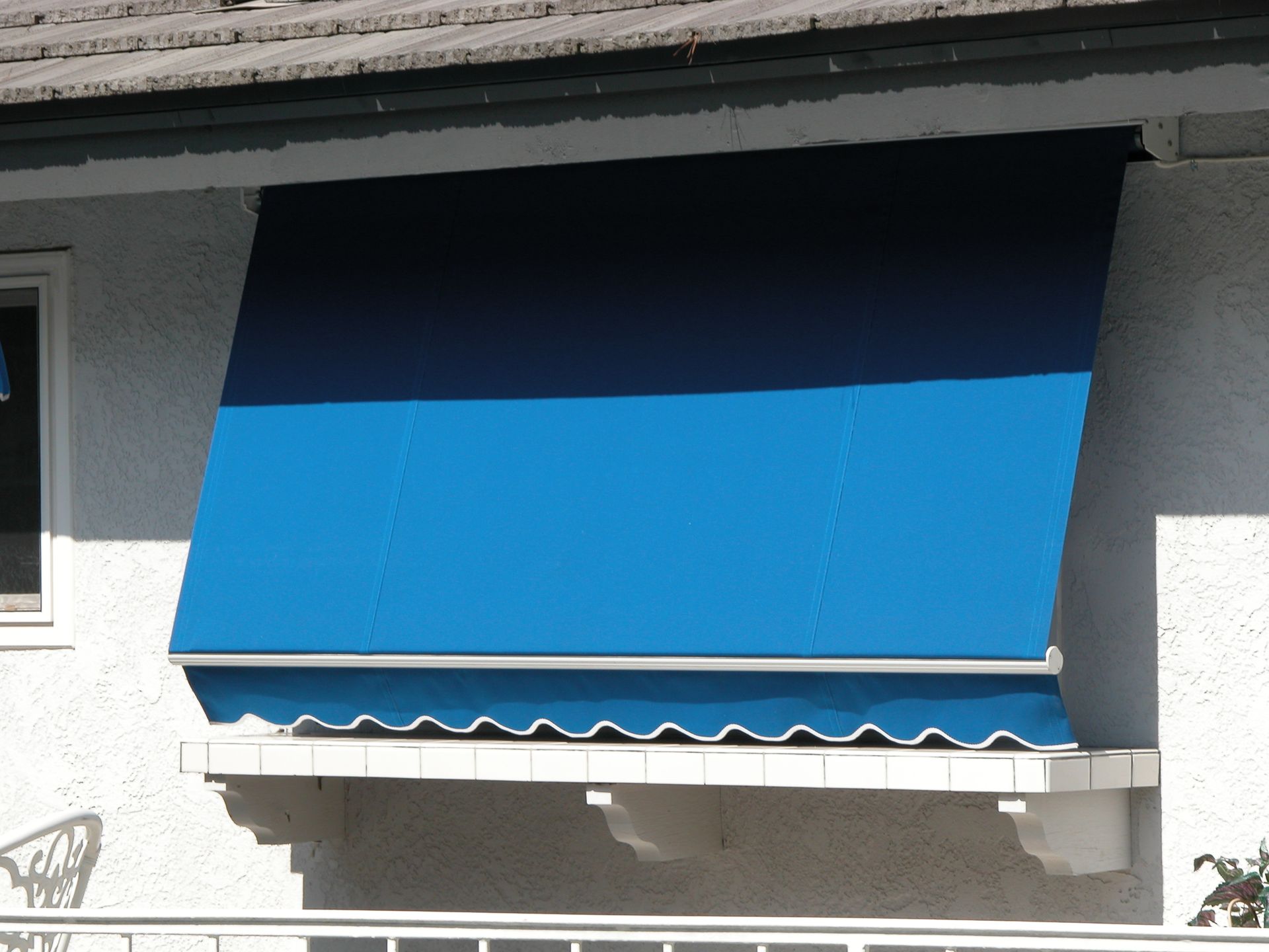 A blue awning is hanging from the side of a building