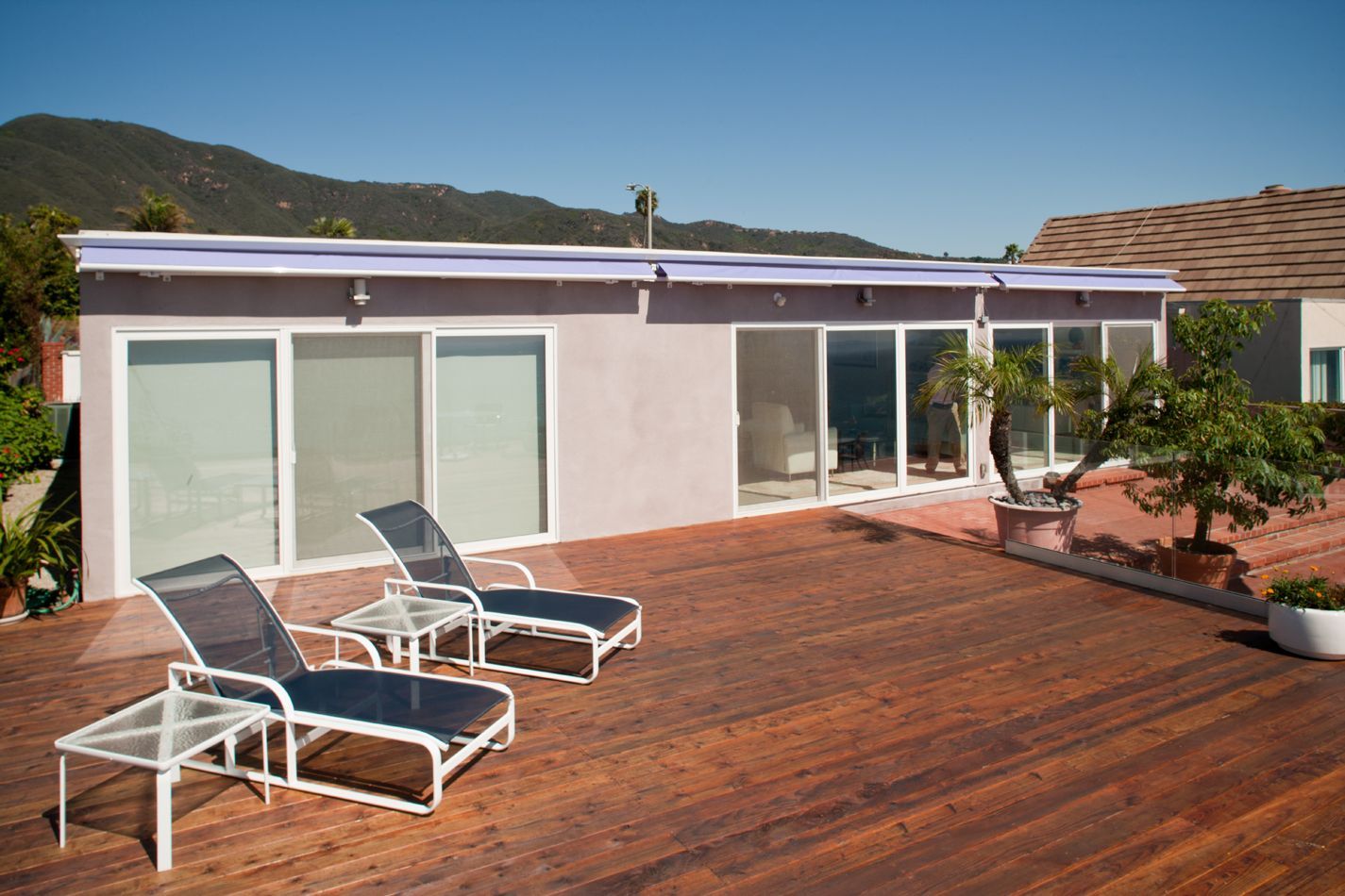 Two lounge chairs are sitting on a wooden deck in front of a house.