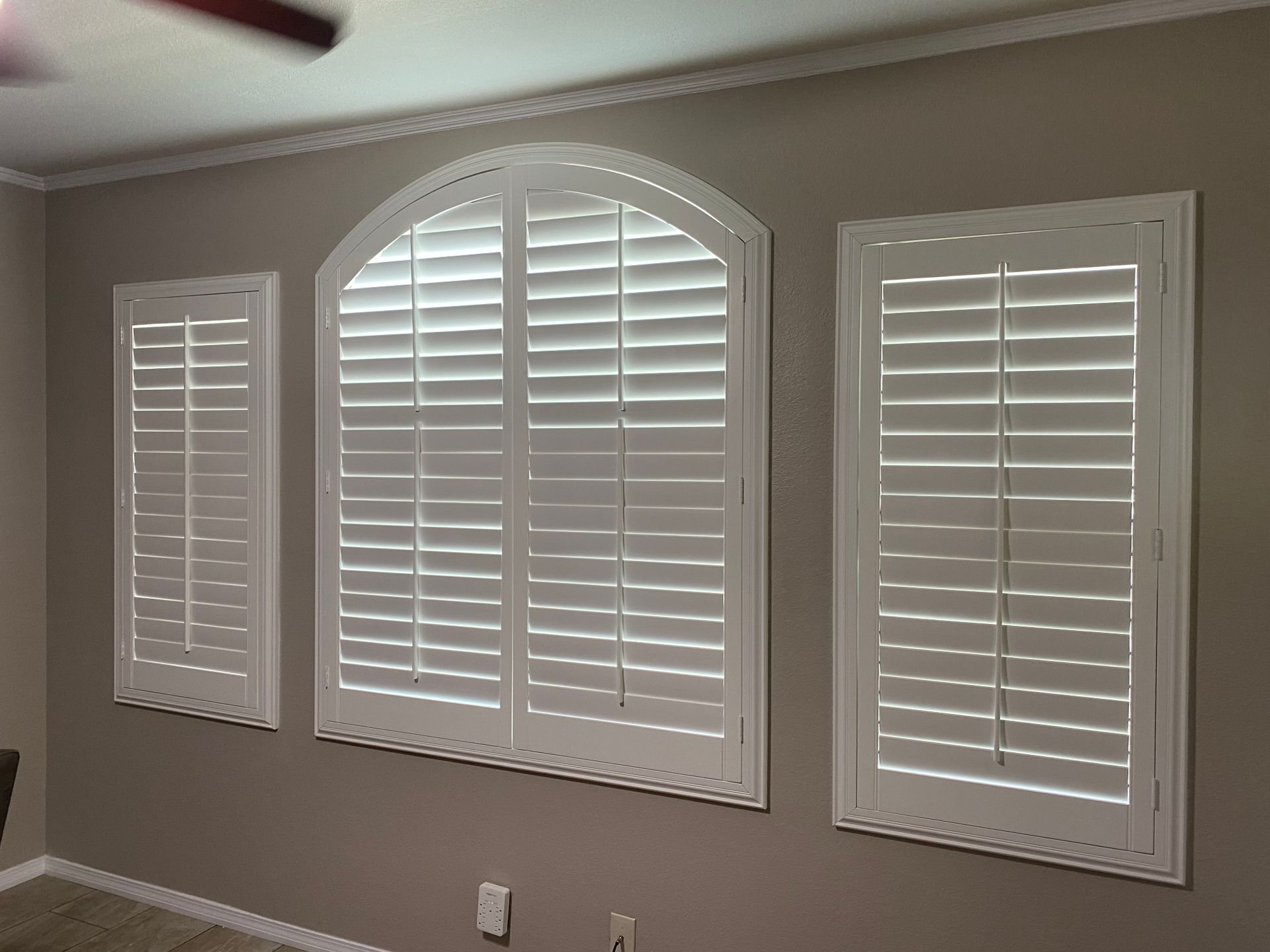 A bedroom with arched windows and white shutters