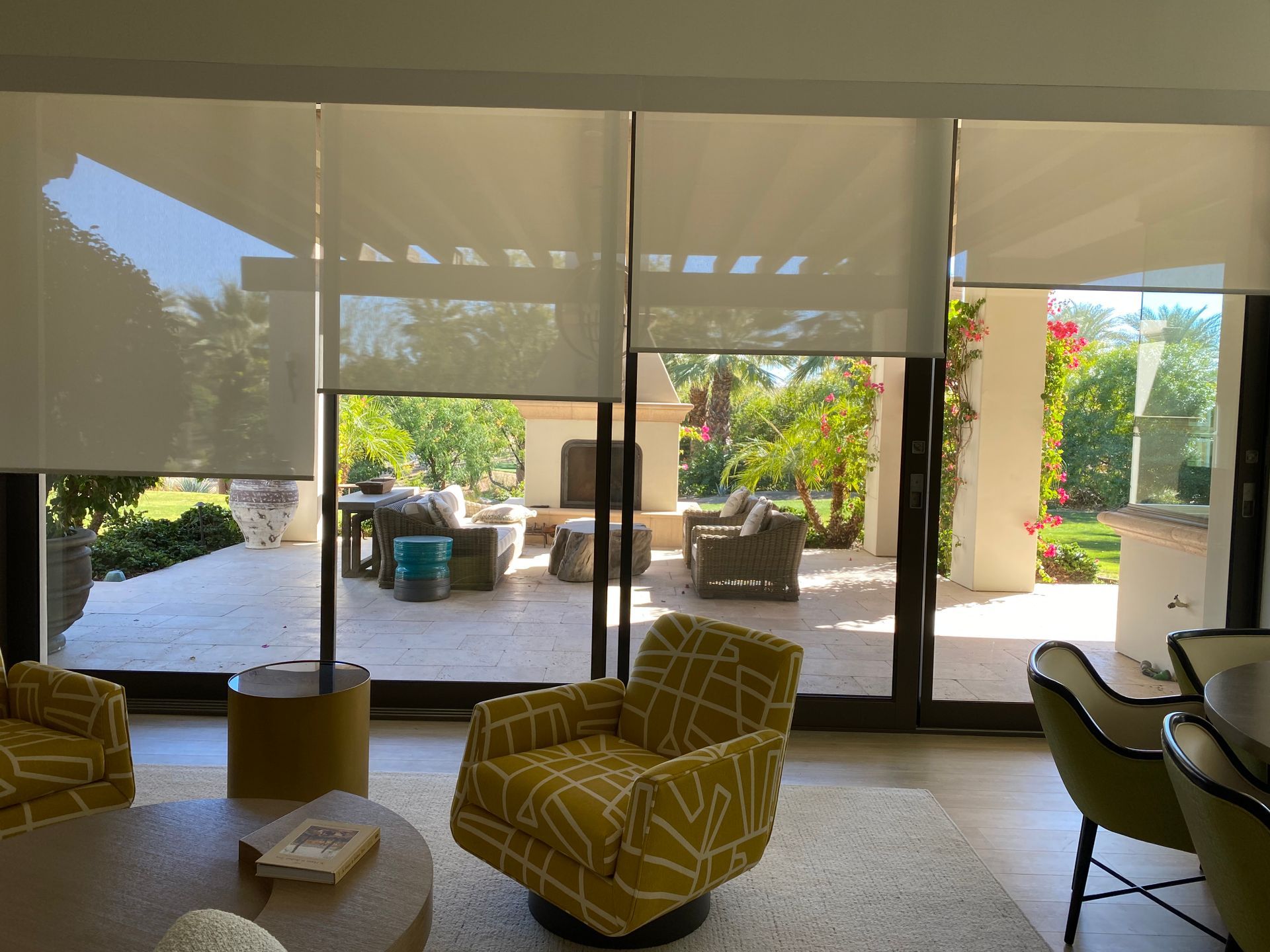 A living room with a yellow chair , table , and sliding glass doors.