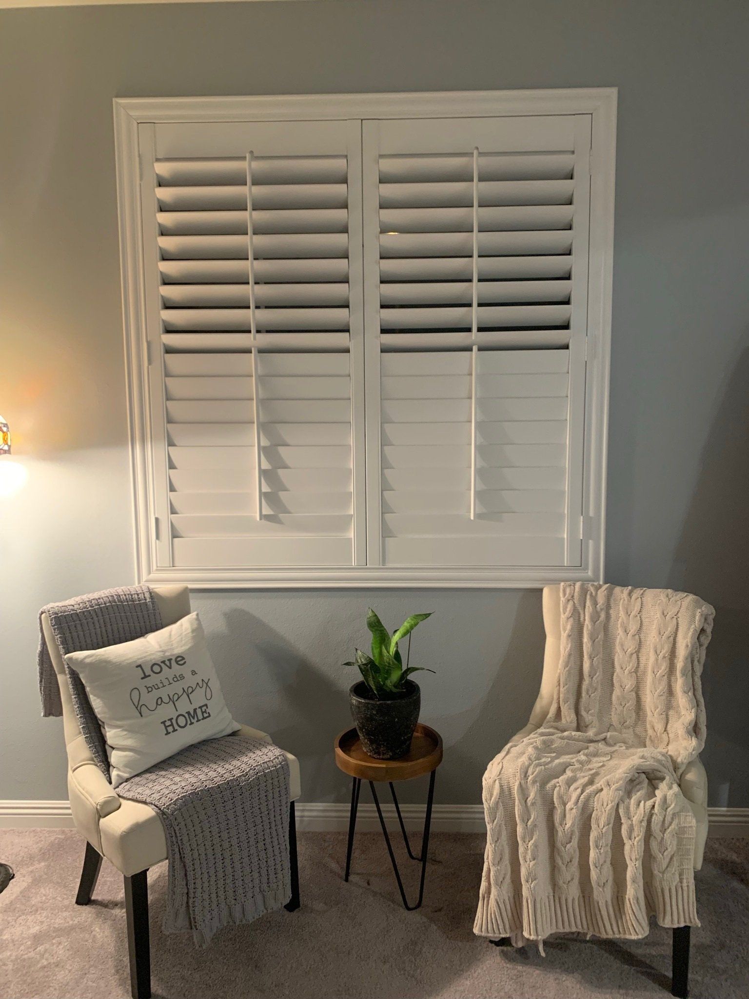 A living room with two chairs and a window with shutters.
