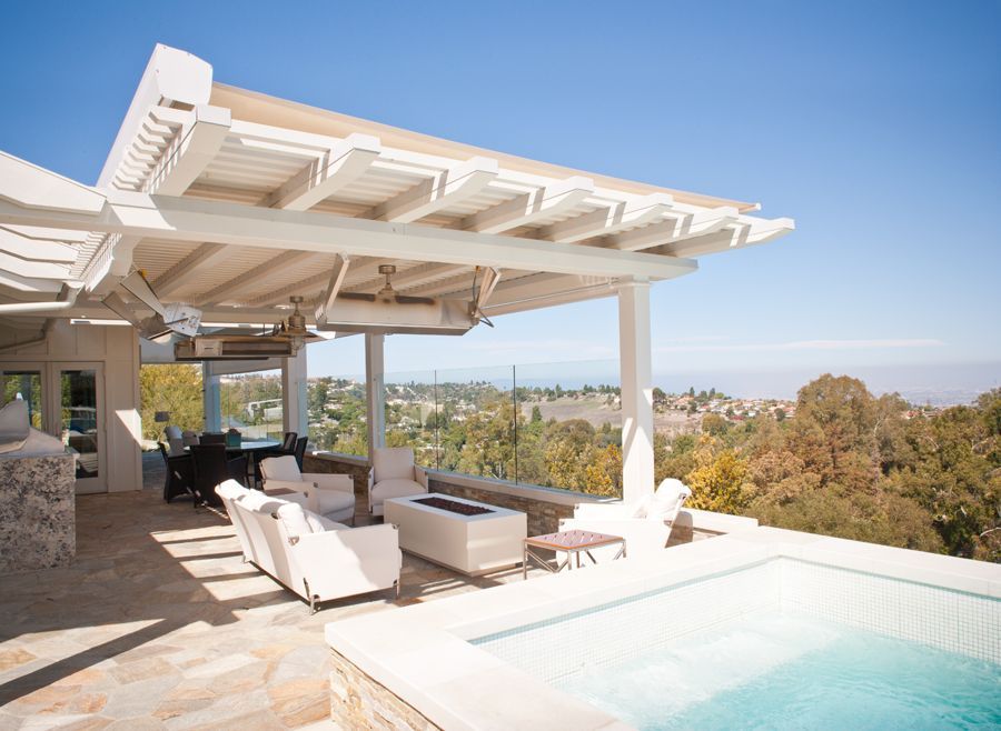 A patio with a pergola overlooking a swimming pool.