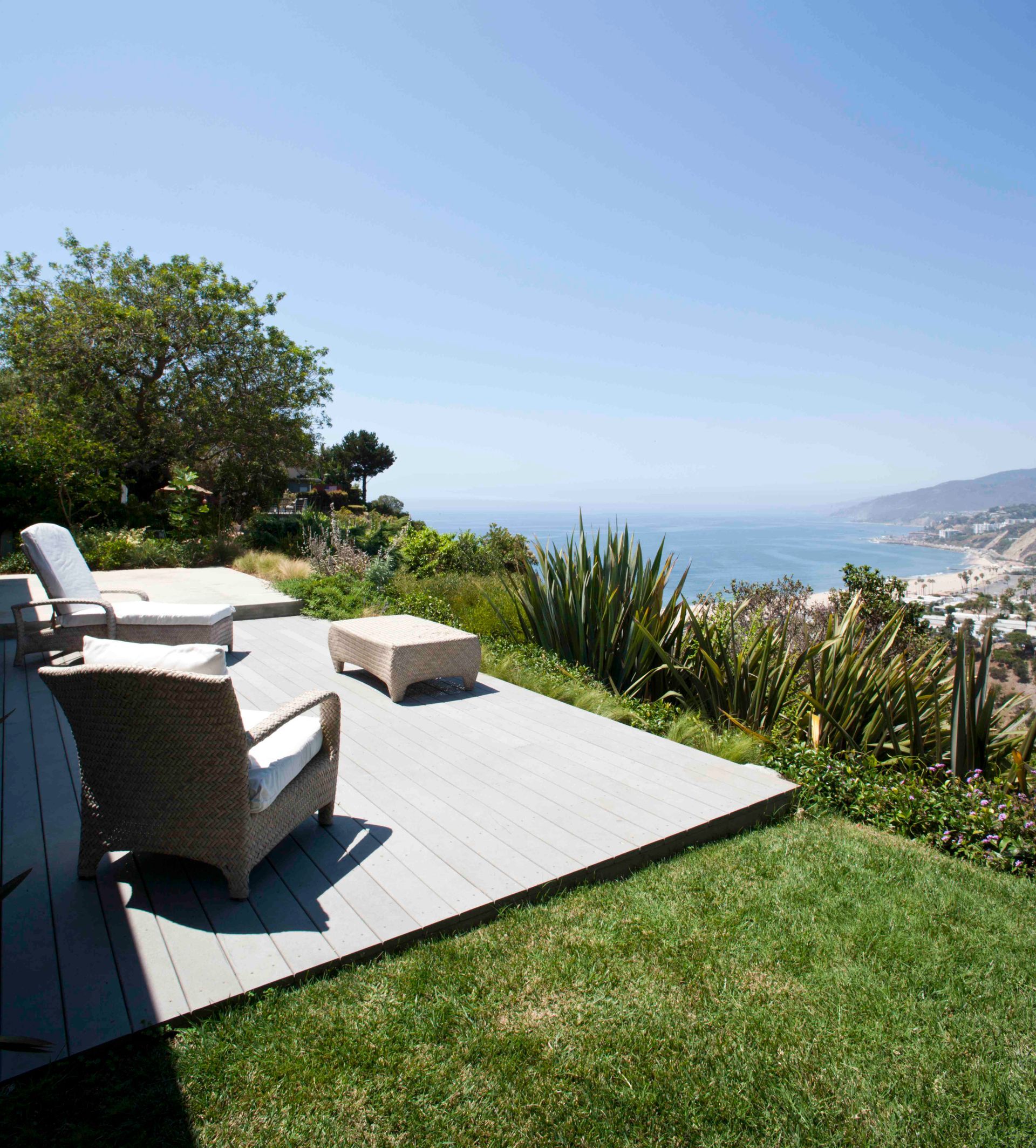 A patio with chairs and a table overlooking the ocean.