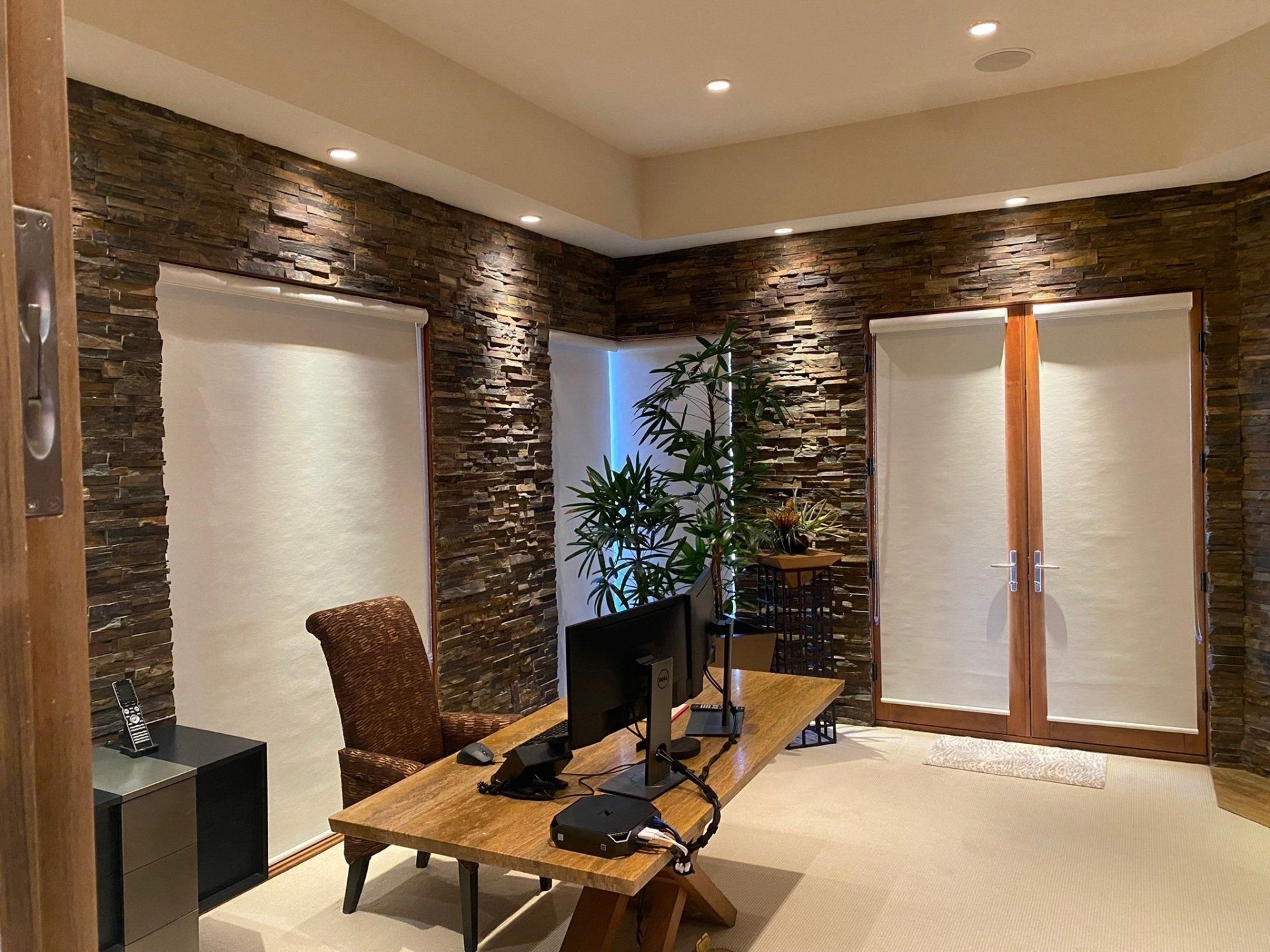 There is a desk with a computer on it in a room with a brick wall.