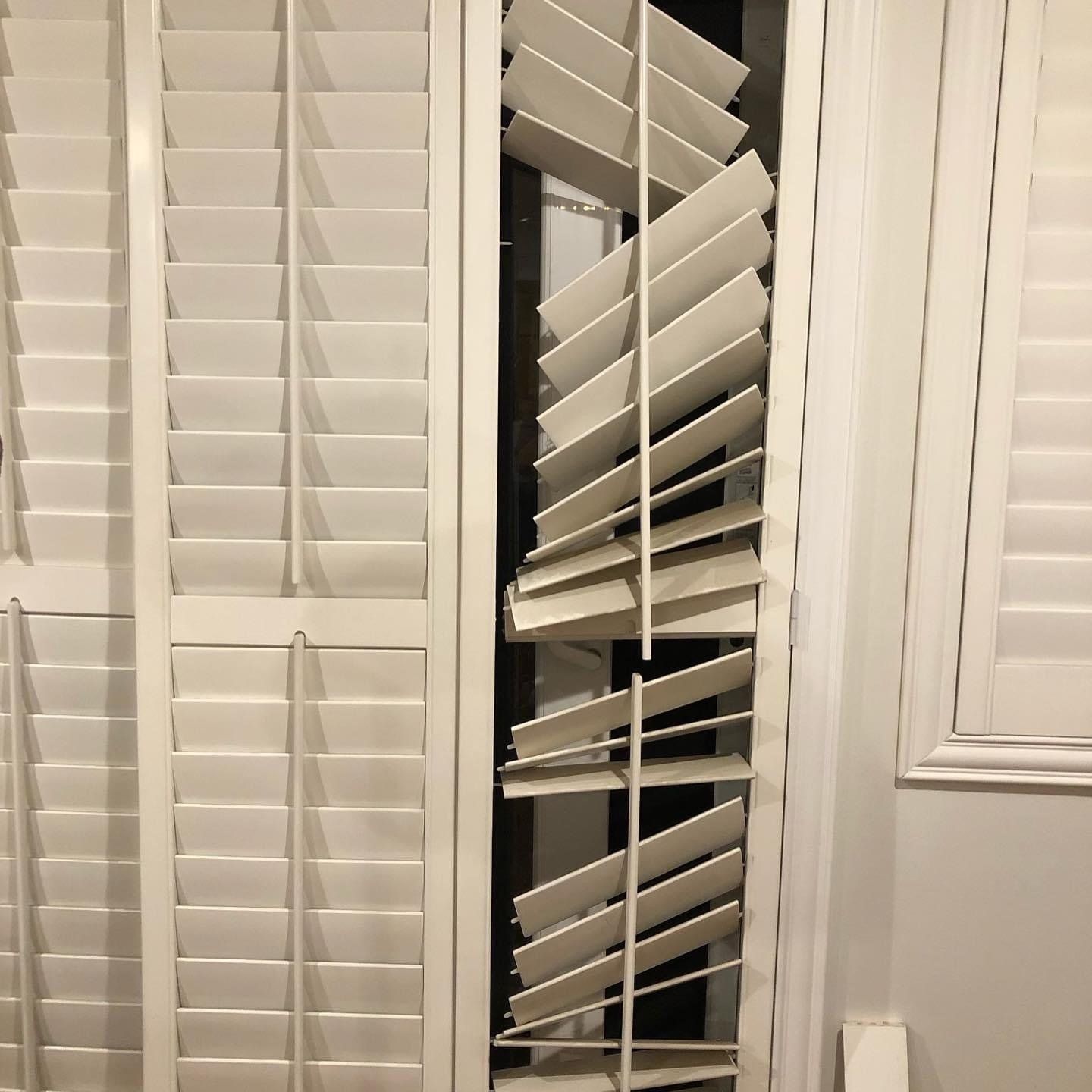 A pair of white shutters are open on a window.