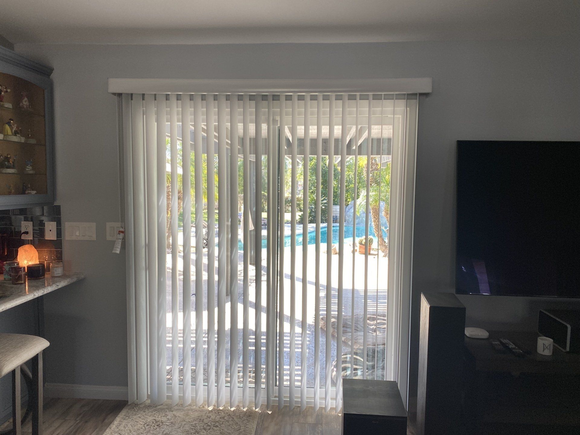 A living room with a sliding glass door and vertical blinds.