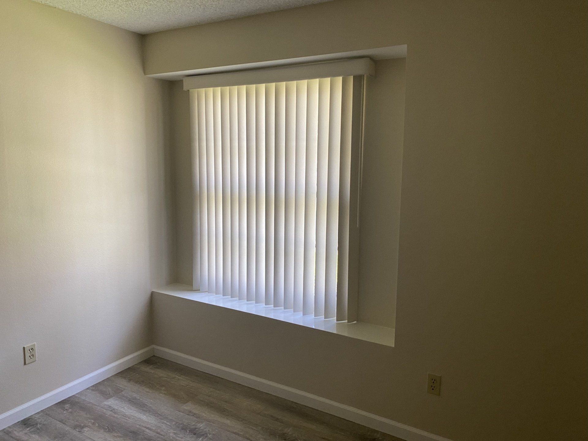 A bedroom with a window and blinds on it.