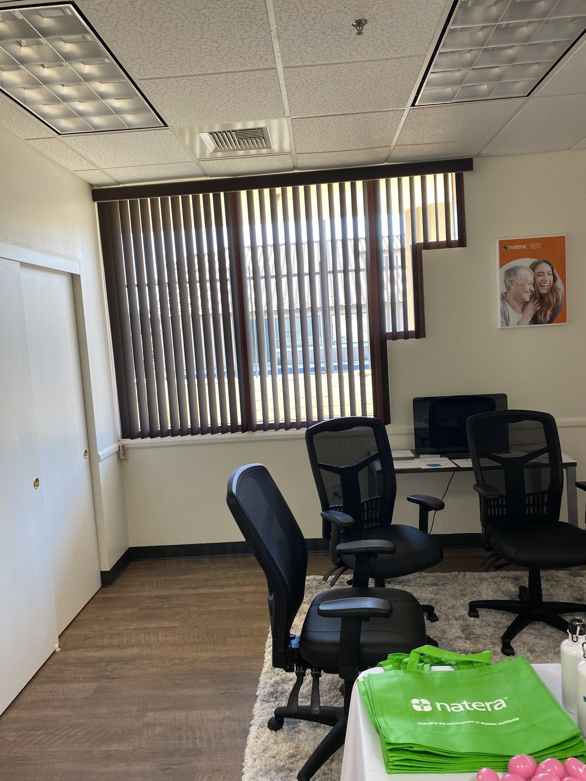 A room with chairs , a desk and a window with blinds.