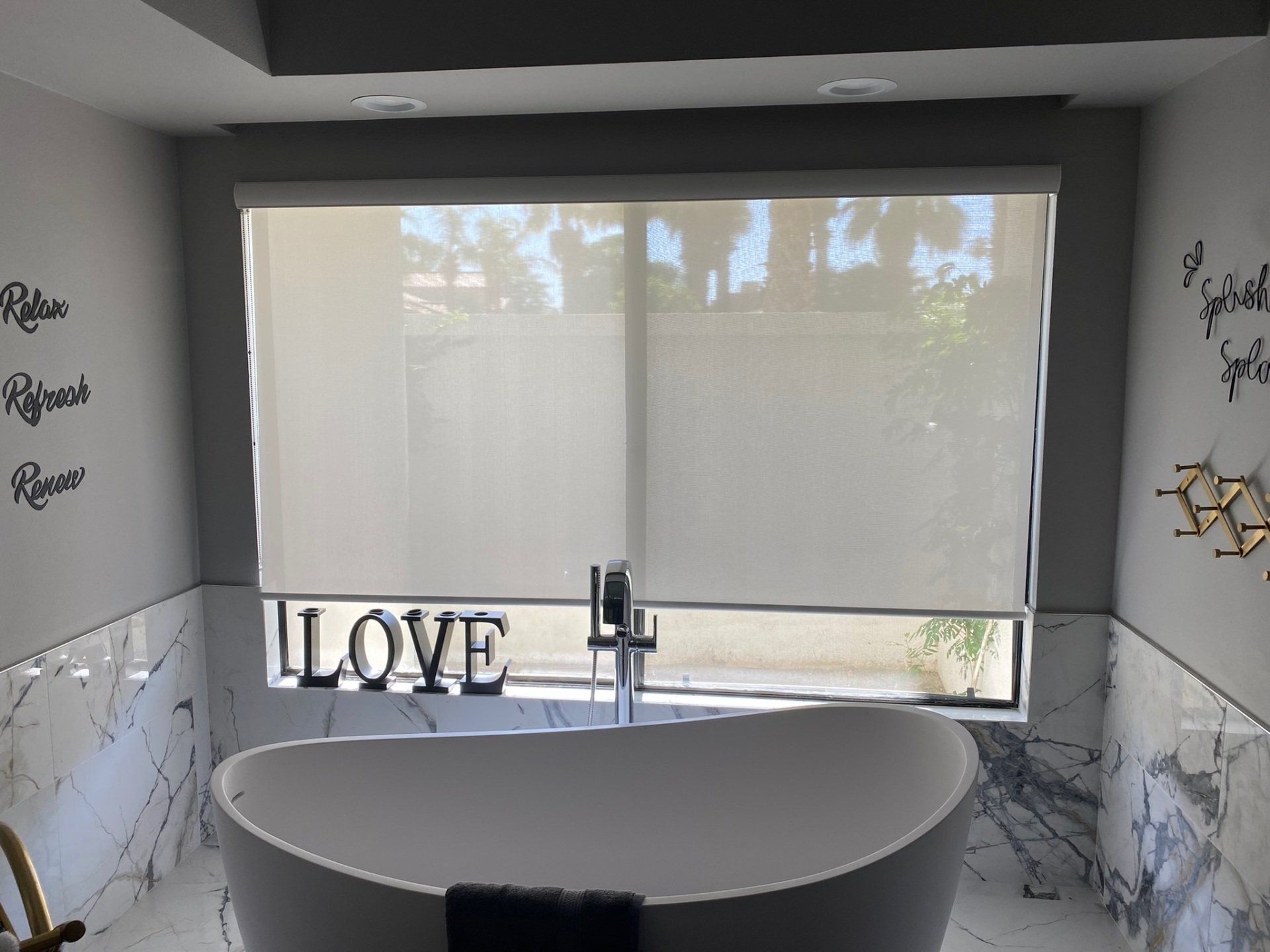 A bathroom with a bathtub and a window with a sign that says `` love ''.