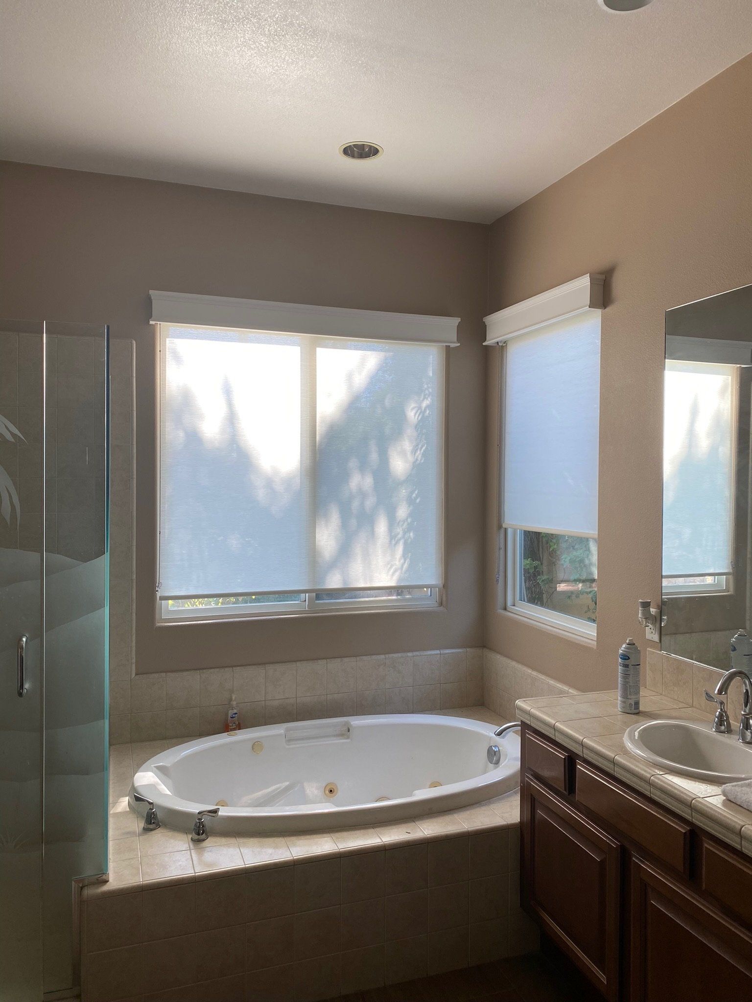 A bathroom with a tub , sink , mirror and window.