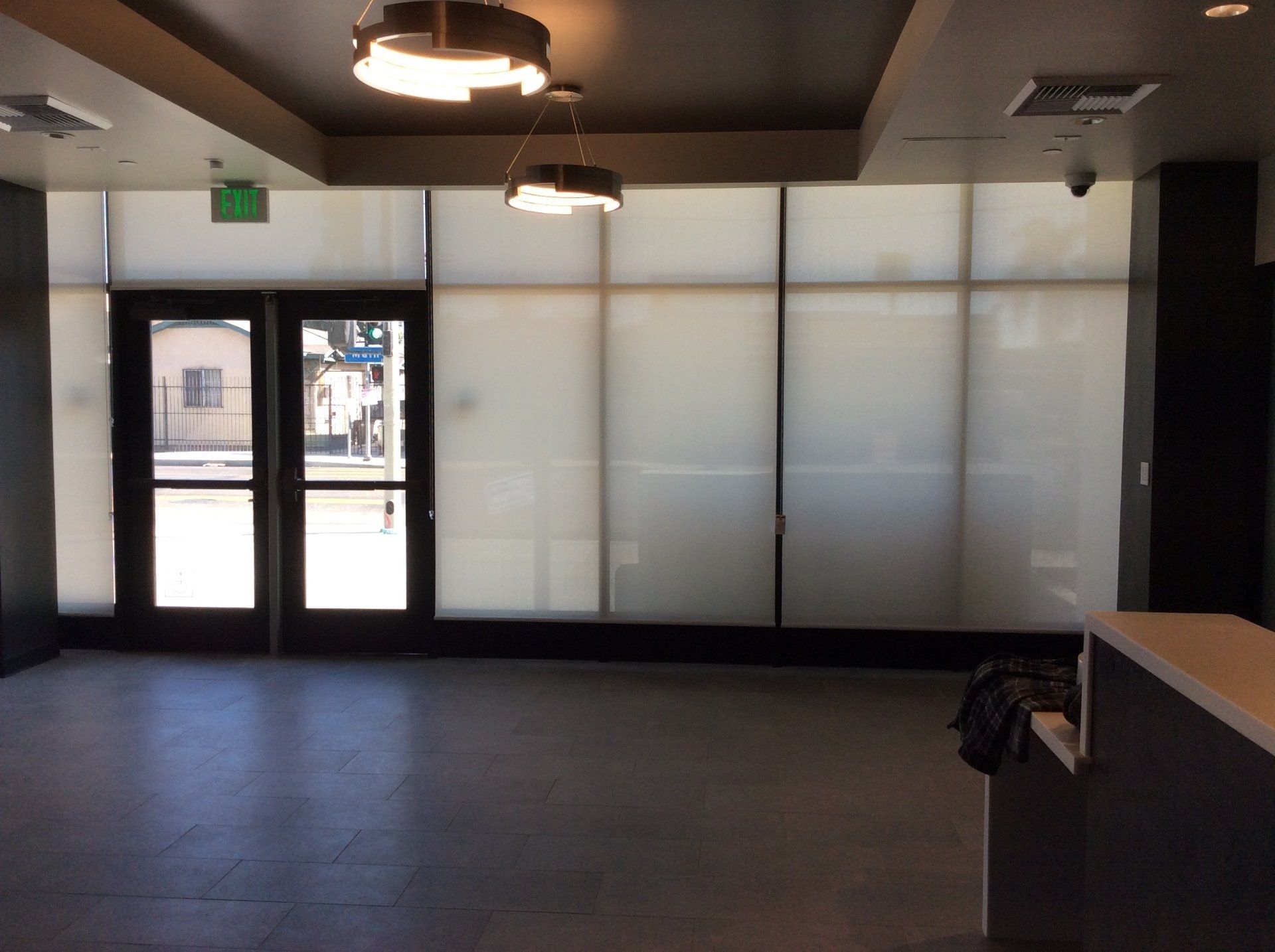 An empty room with a green exit sign on the ceiling