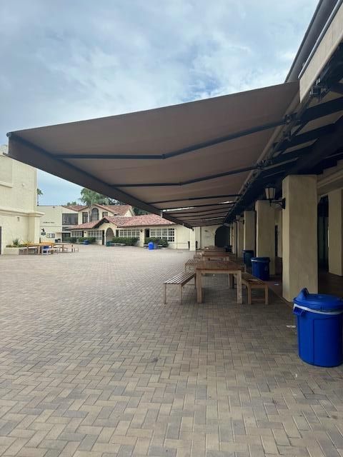 A large awning over a brick courtyard with tables and benches
