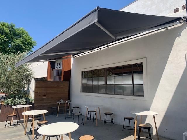 A white building with tables and chairs under an awning