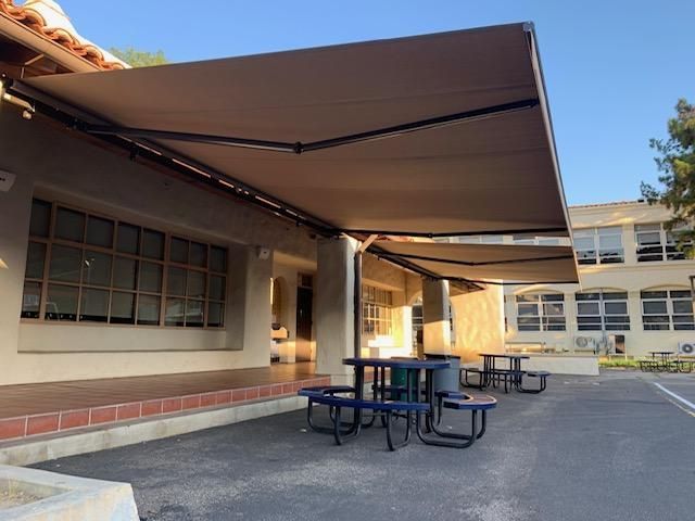 A picnic area with tables and chairs under an awning