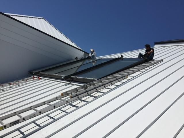 Two men are working on a white roof