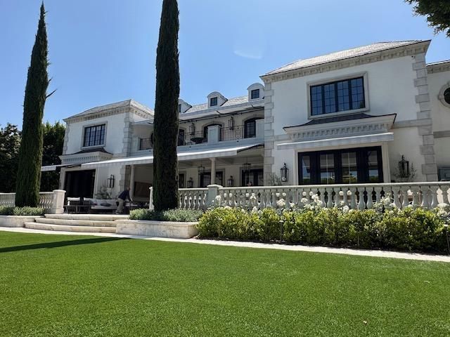 A large white house with a lush green lawn in front of it.