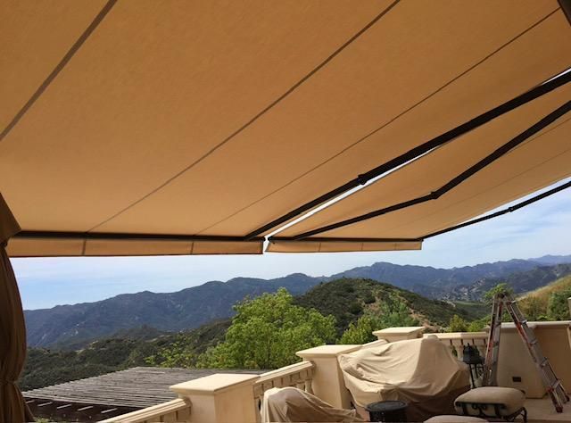 A balcony with an awning over it and mountains in the background