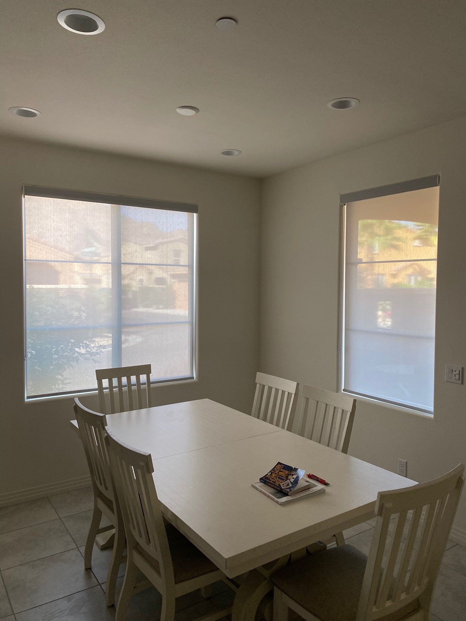 A dining room with a table and chairs and lots of windows