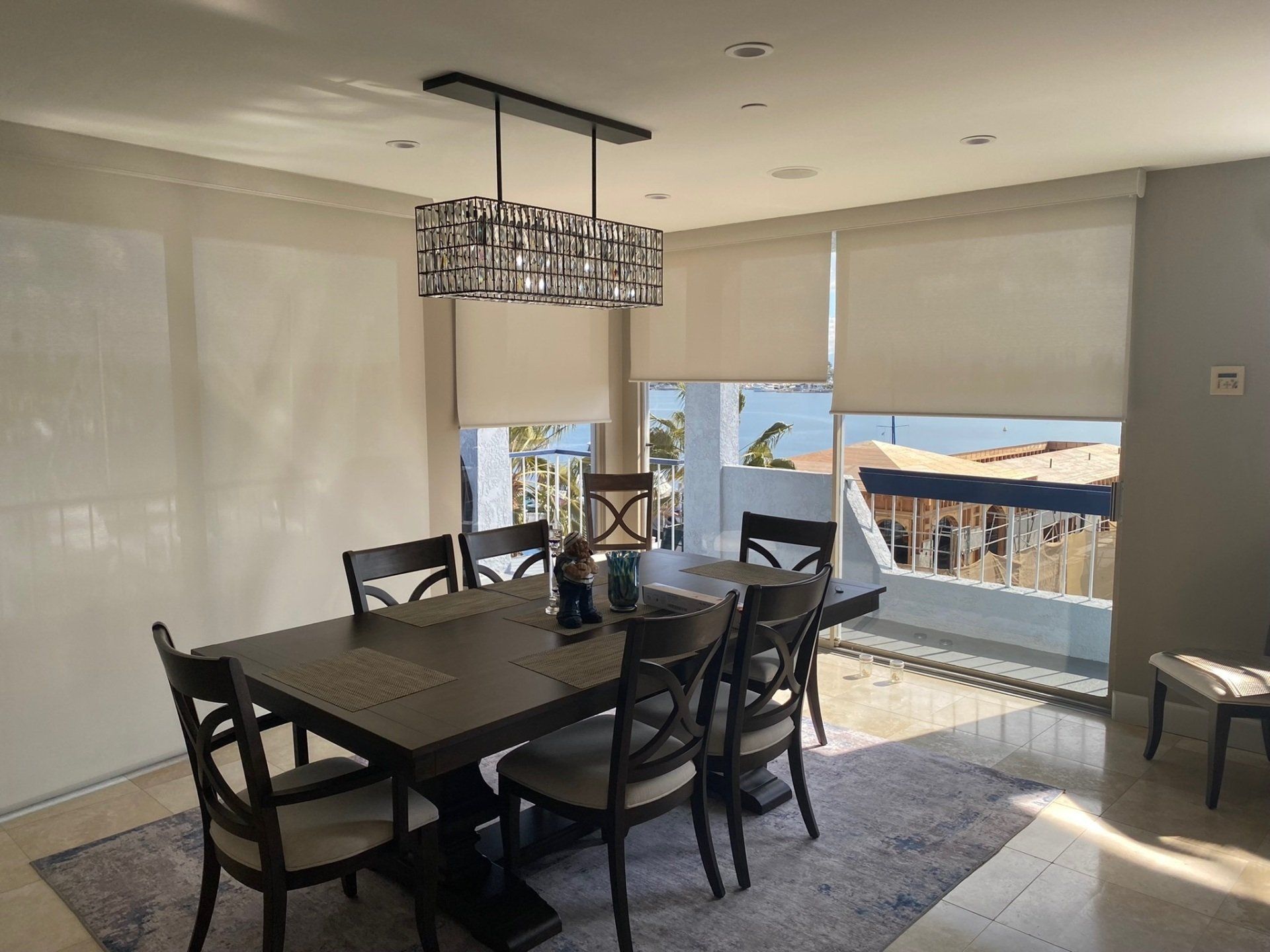 A dining room with a table and chairs and blinds on the windows.