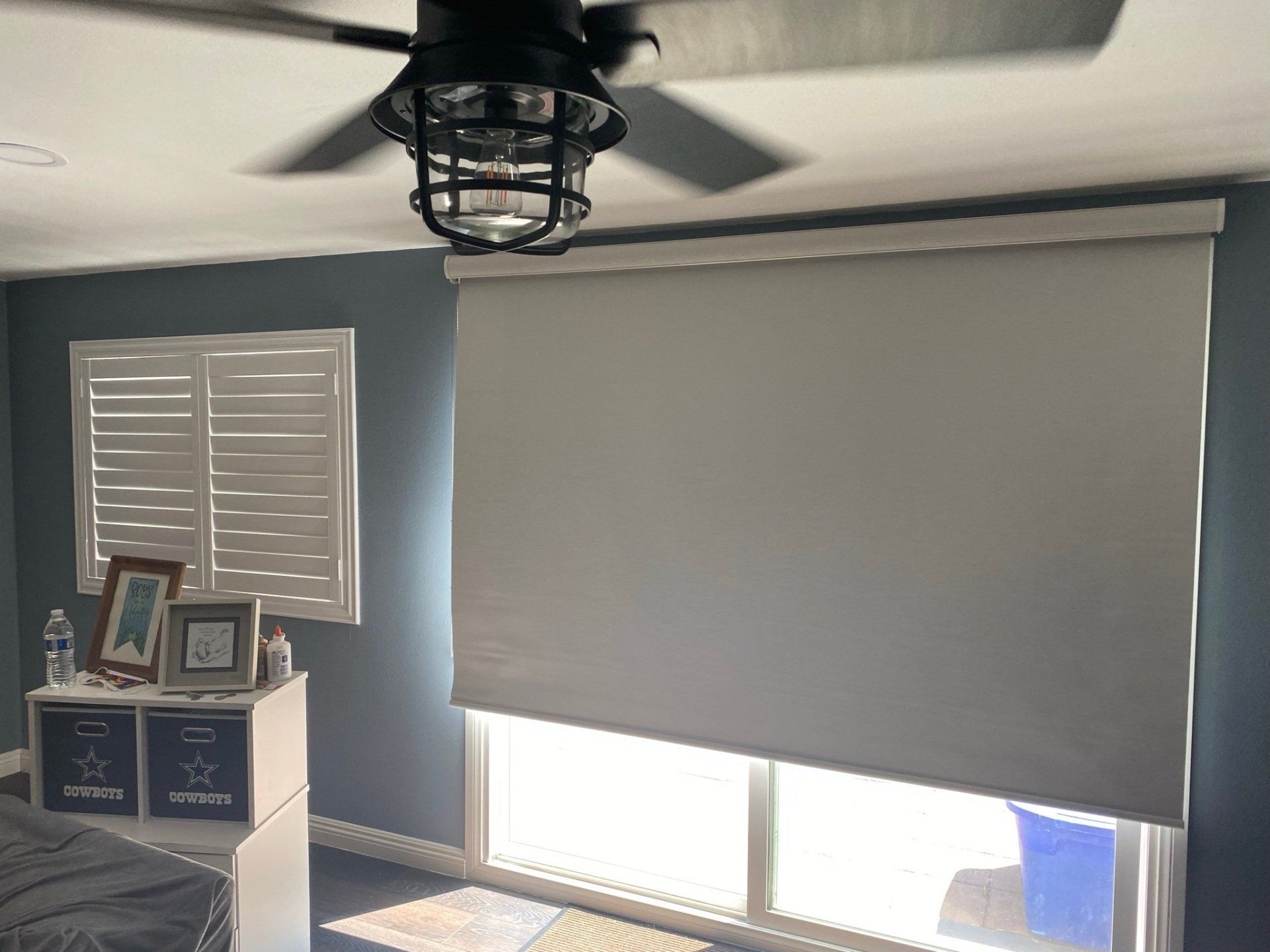 A bedroom with a ceiling fan and a window with blinds.