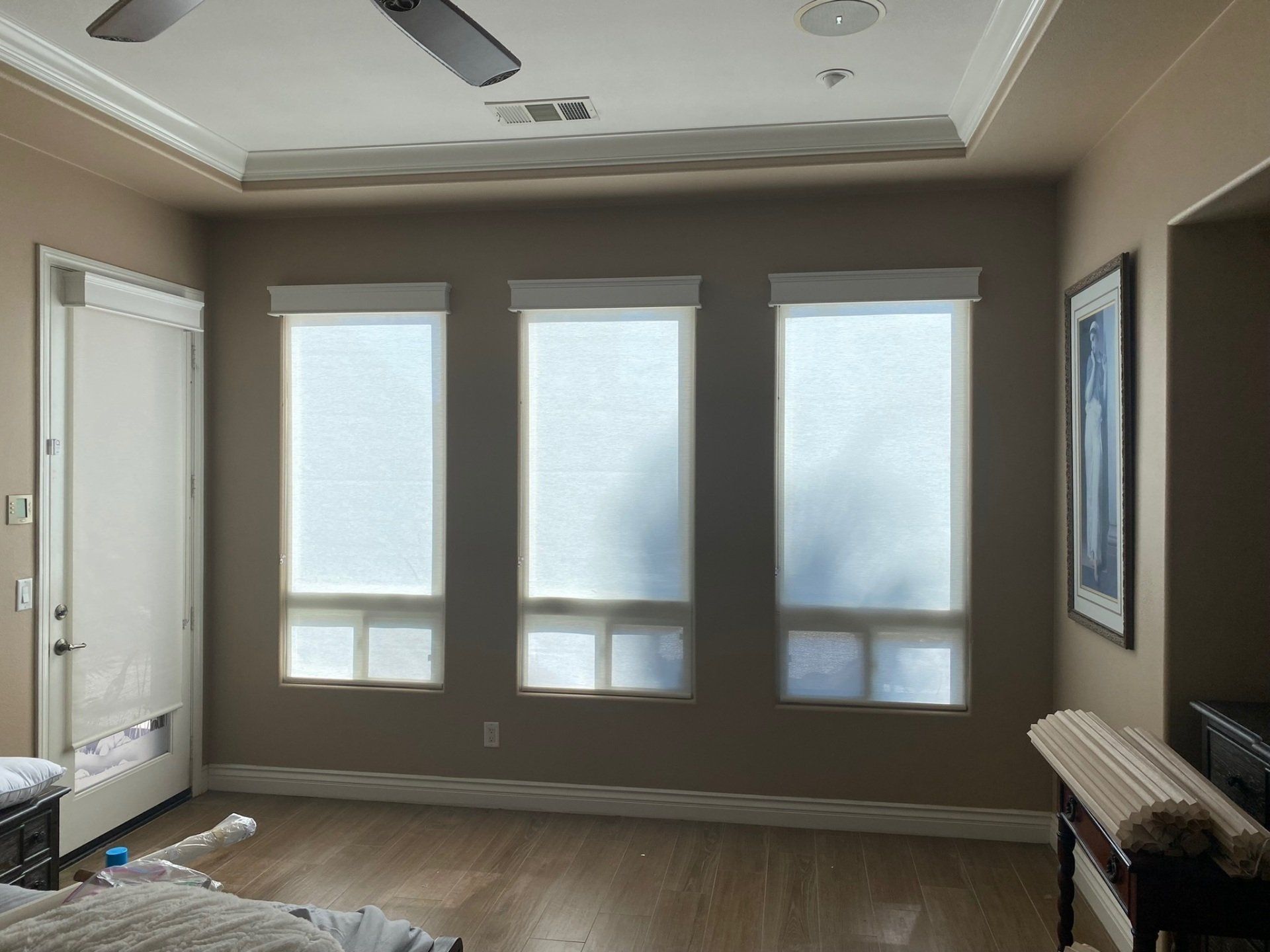 A bedroom with three windows and a ceiling fan