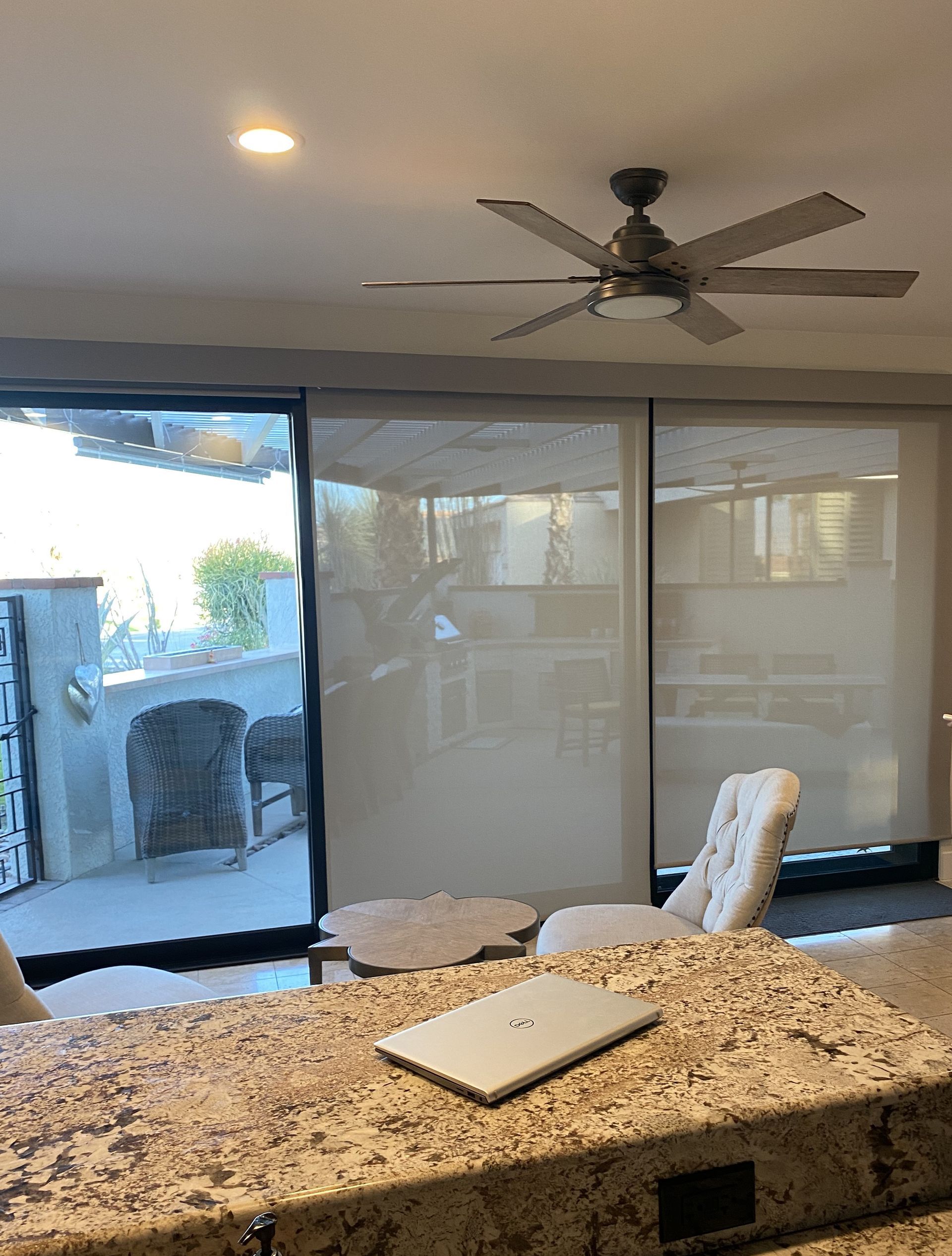 A kitchen with a laptop on the counter and a ceiling fan.