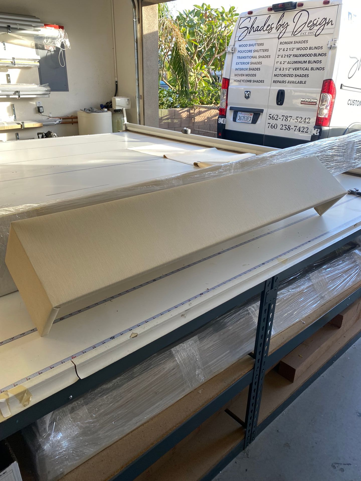 A white van is parked in a garage next to a table with a piece of wood on it.