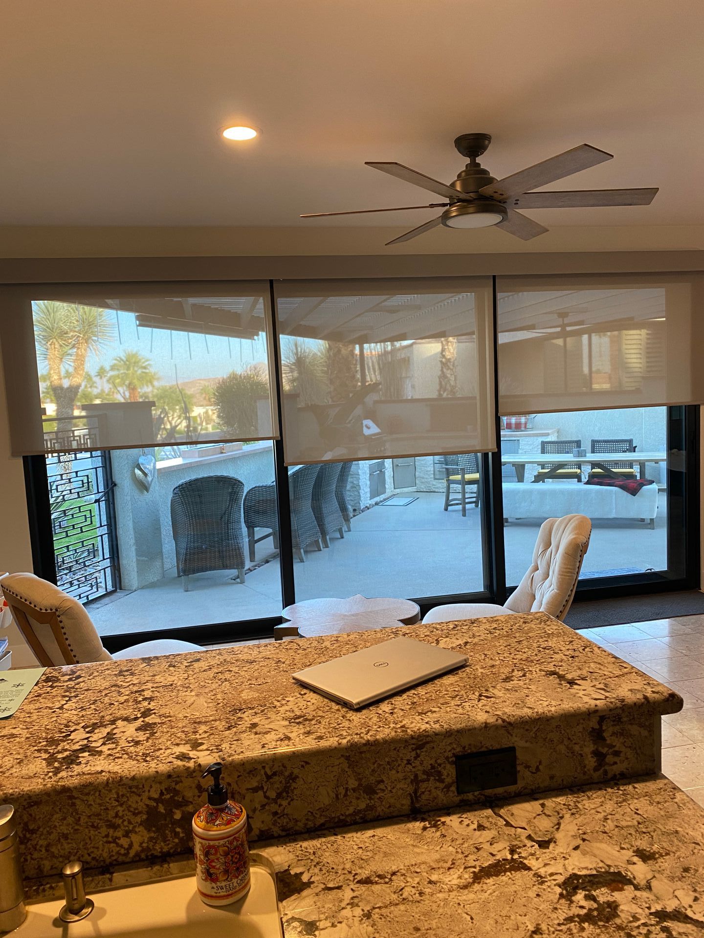A kitchen with a laptop on the counter and a ceiling fan.