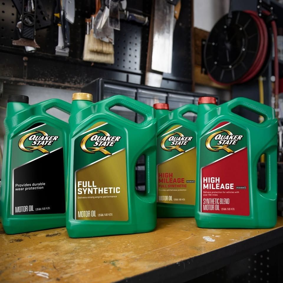 Four green Quaker State motor oil containers on a workbench, labeled: