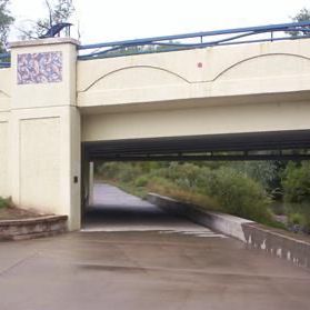 A pedestrian tunnel under a bridge; beige and concrete, with a pathway leading through.