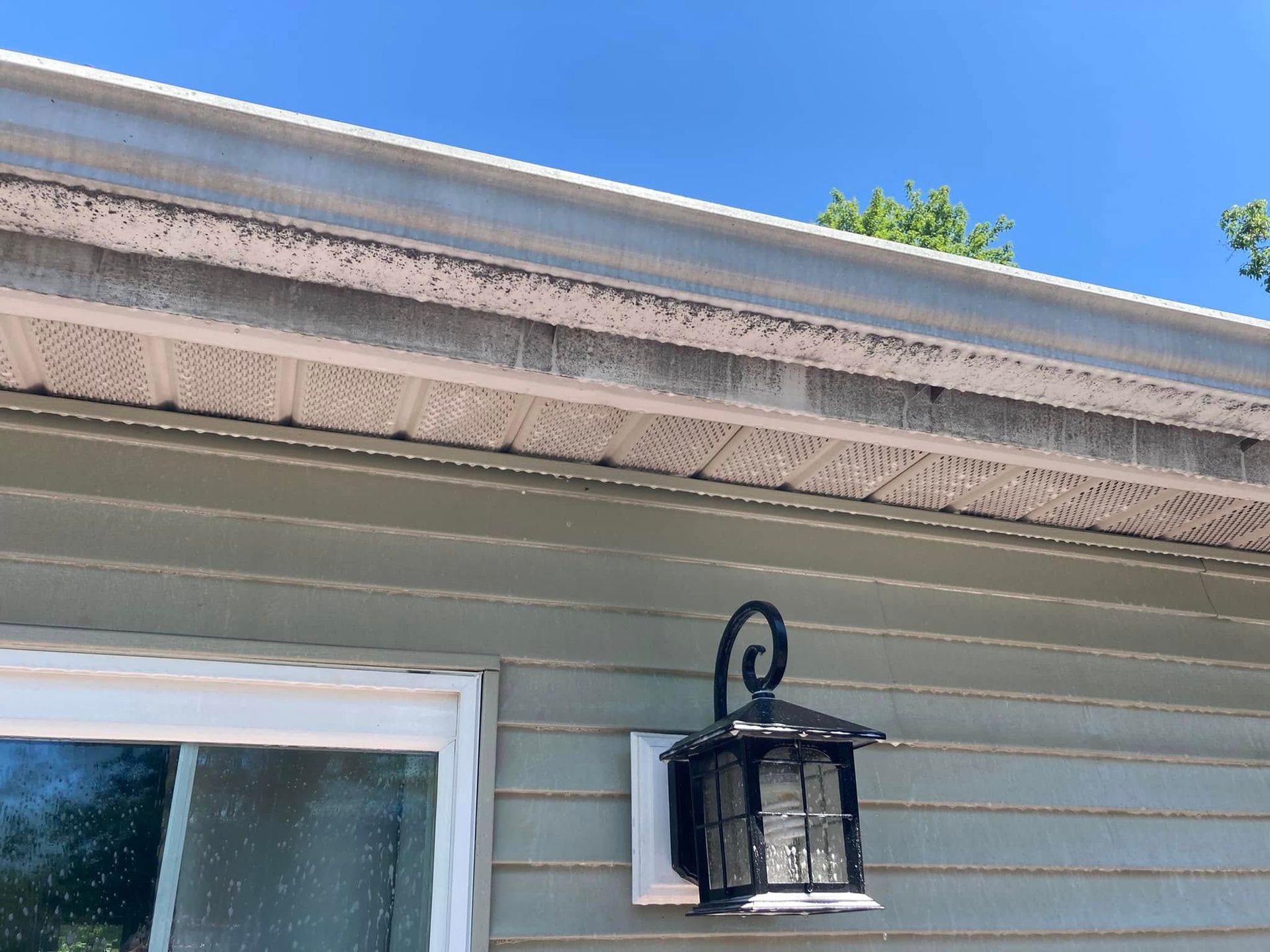 A light on the side of a house with a blue sky in the background.