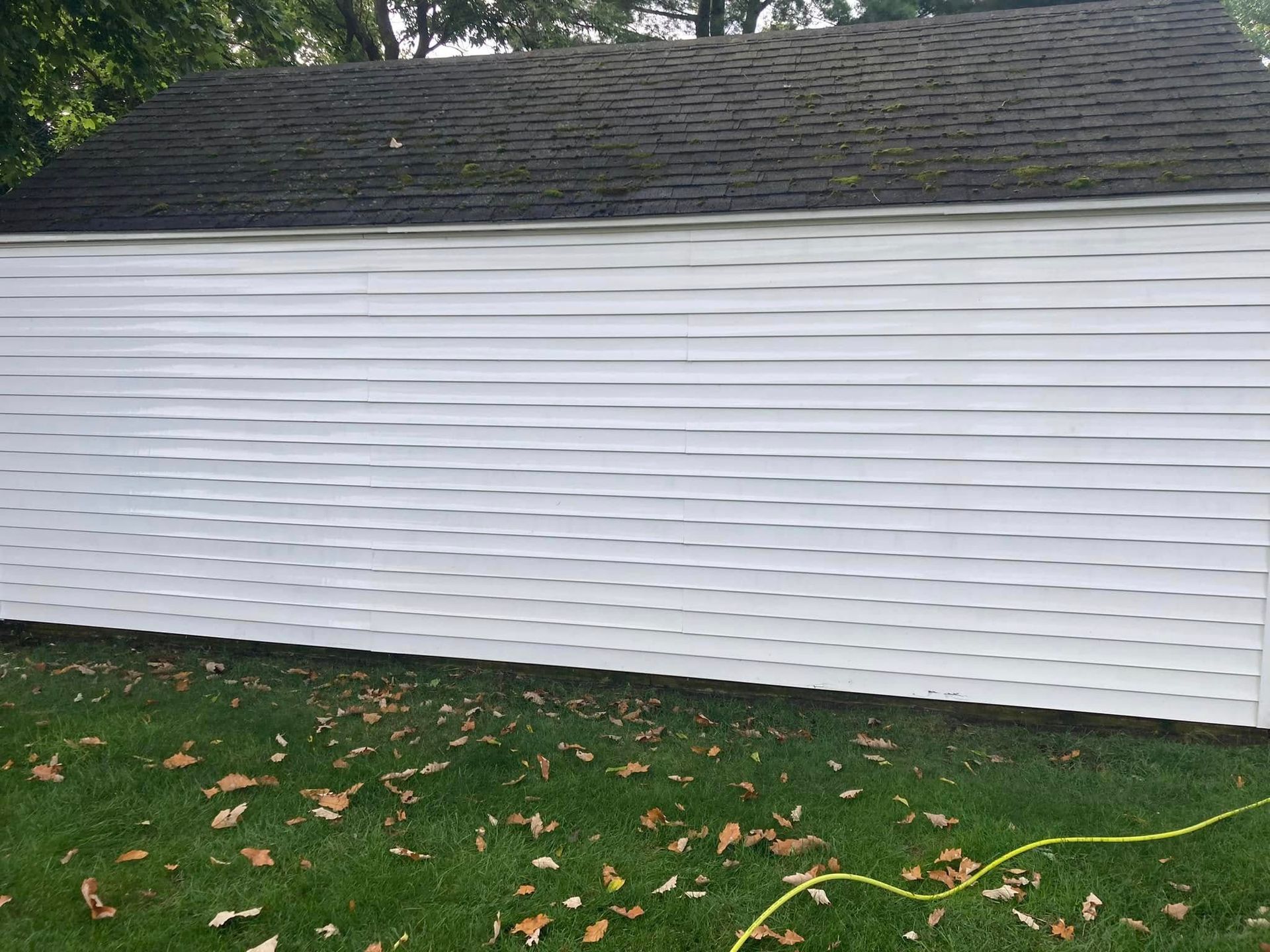 A white fence is sitting in the grass in front of a house.