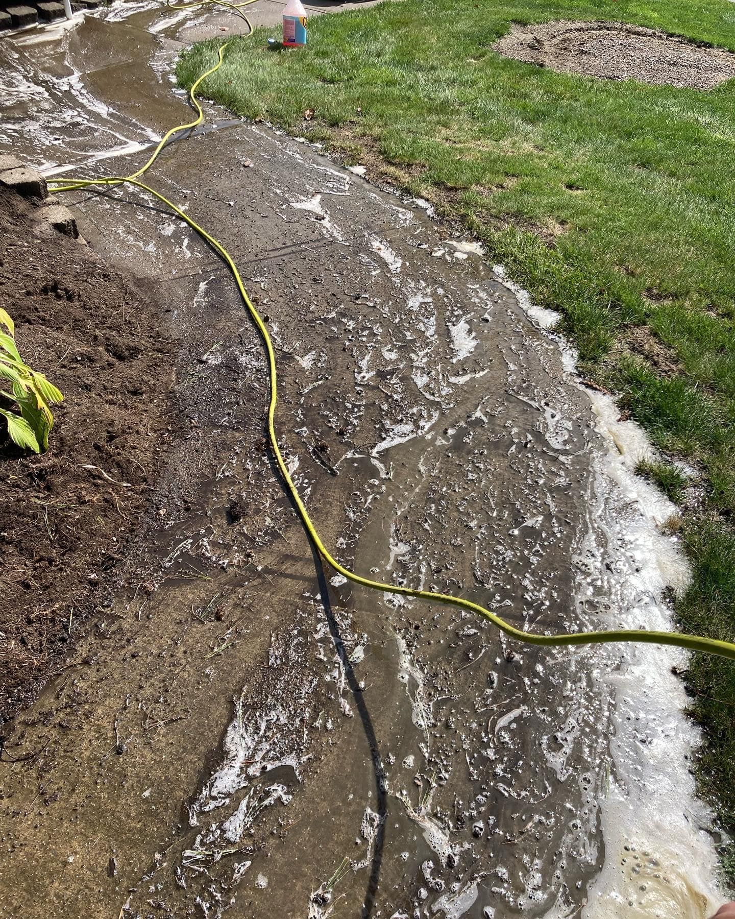 A hose is being used to clean a muddy sidewalk.