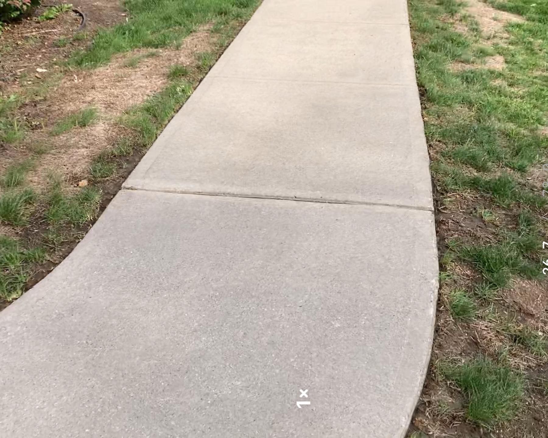 A concrete sidewalk with grass on the side of it.
