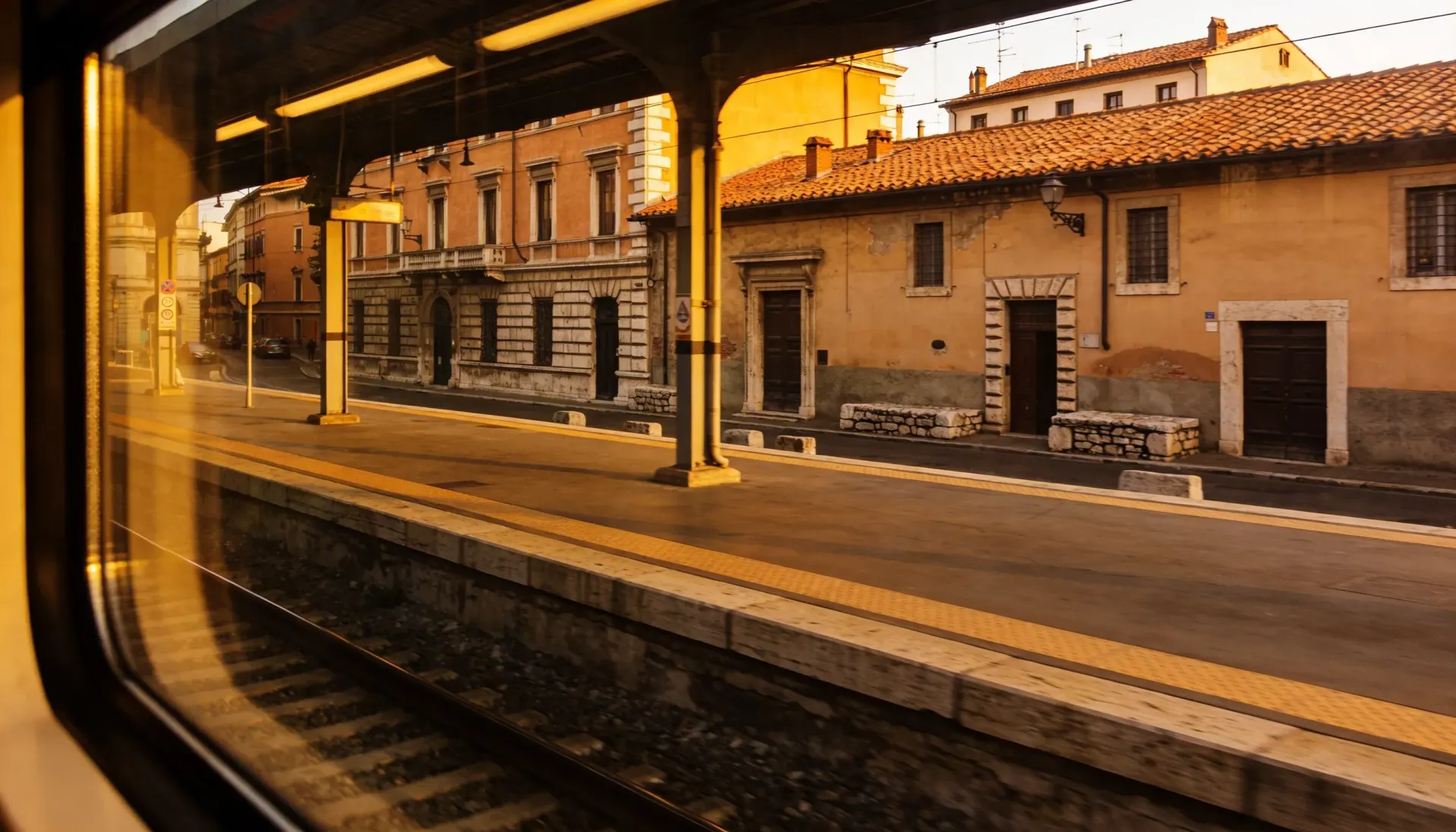Train station platform with old buildings in warm sunlight.